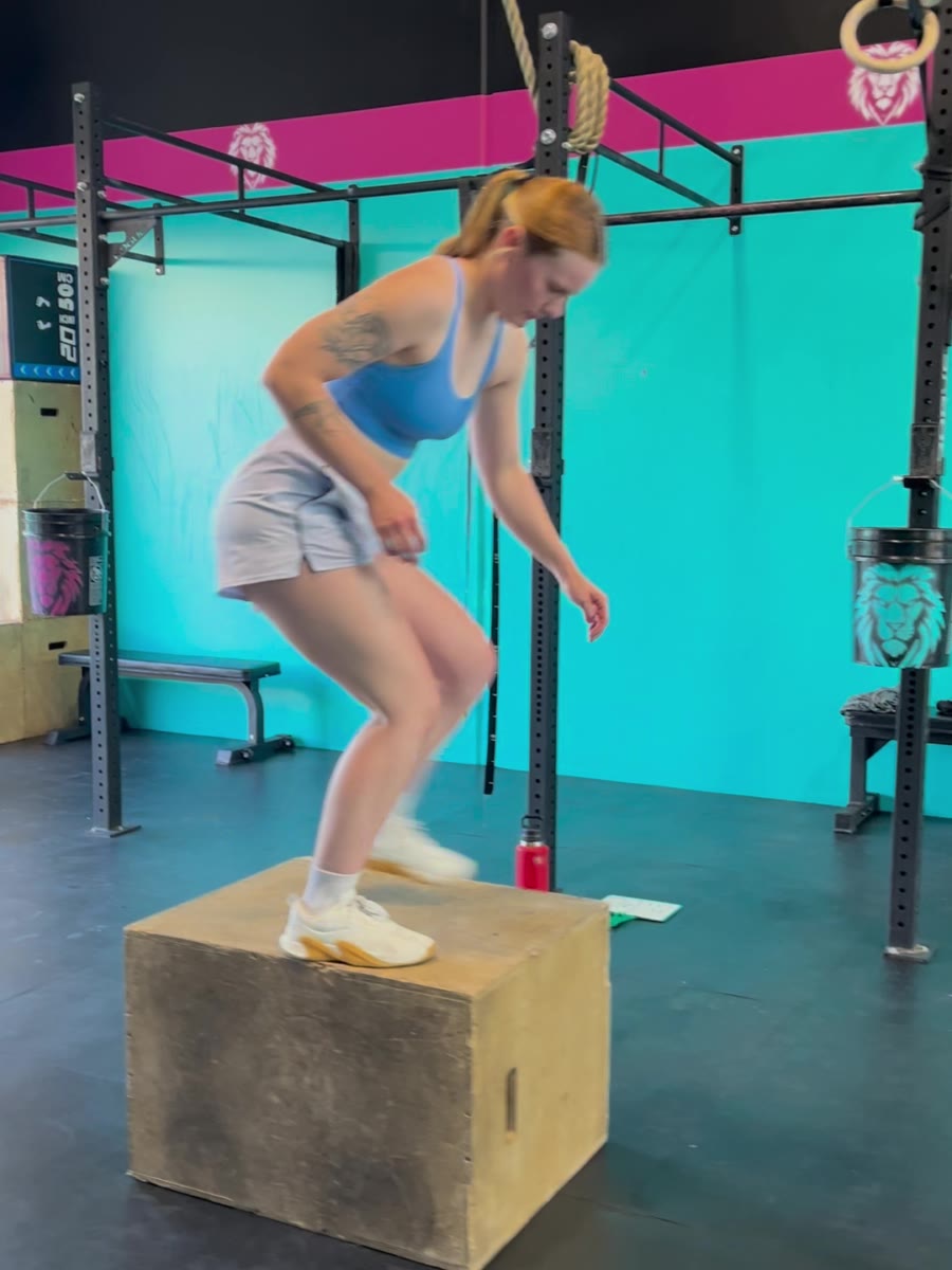 An EPPIC member in a blue top doing box work against the turquoise gym wall